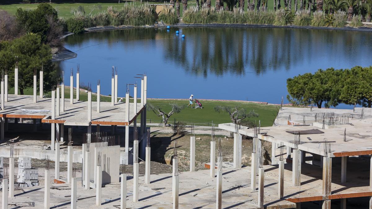 Un jugador camina por el campo de golf de El Plantío entre bloques de apartamentos en estructura