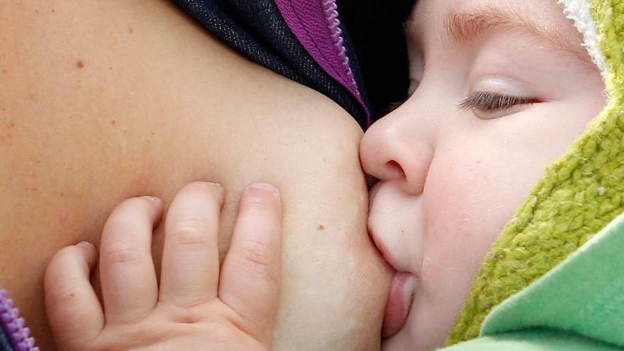 Un niño toma leche del pecho de su madre.