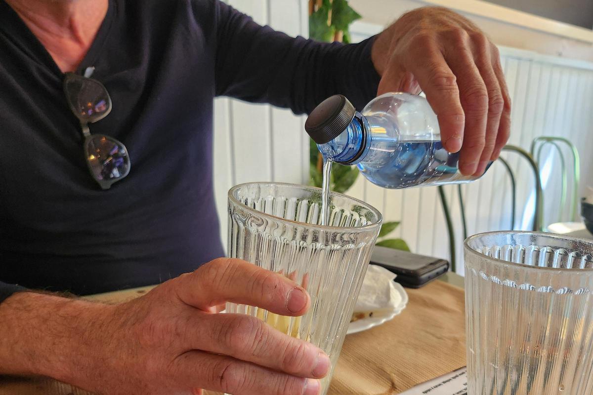 Un hombre se sirve una agua en un vaso en un bar de Vigo.