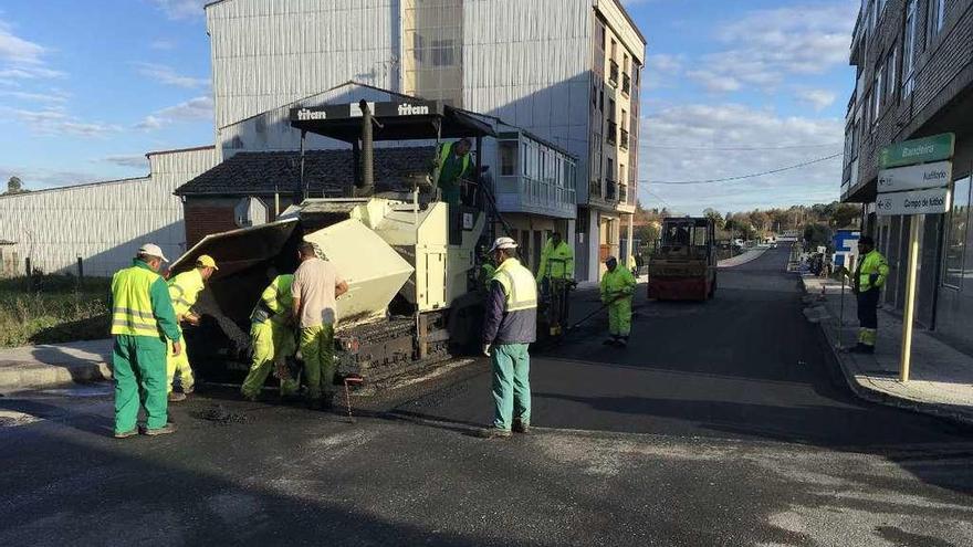 Los operarios aplican aglomerado en caliente en la calle Lourás.