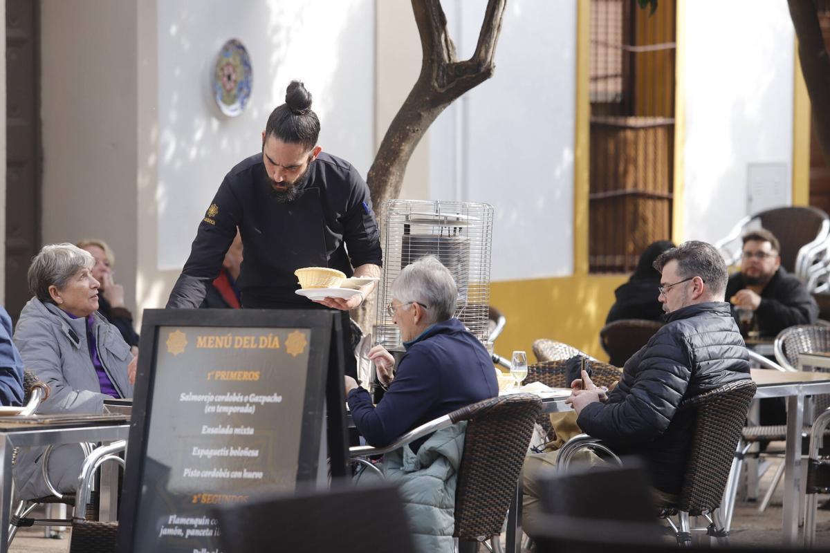 Un camarero atiende a varios comensales en la terraza de un restaurante de Córdoba.