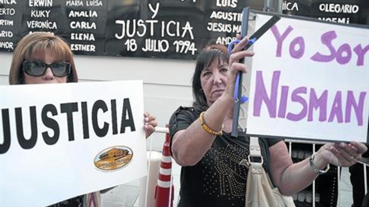 Dos mujeres sostienen pancartas pidiendo justicia frente a la AMIA, en Buenos Aires, este miércoles.