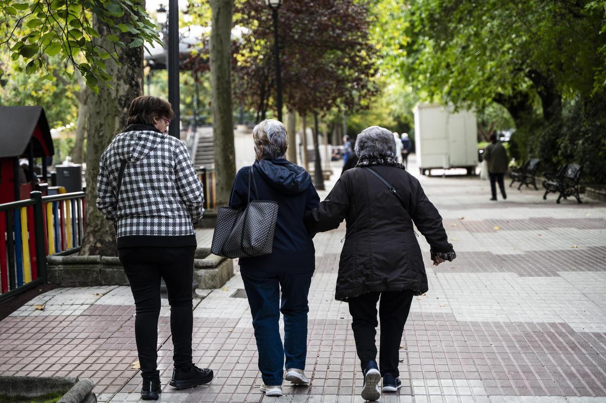 Tres ciudadanos caminan por el paseo de Cánovas.