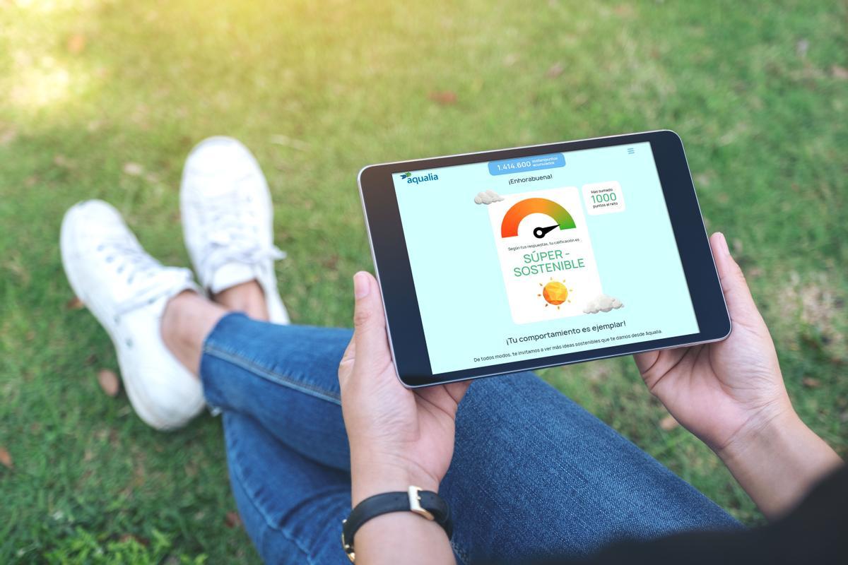 Mockup image of a woman holding and using black tablet pc with blank white desktop screen horizontally while sitting in the outdoors