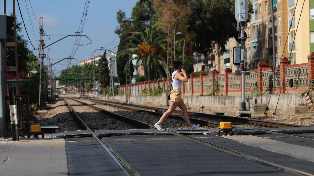 Una mujer cruza las vías hablando con el móvil en Alfafar.