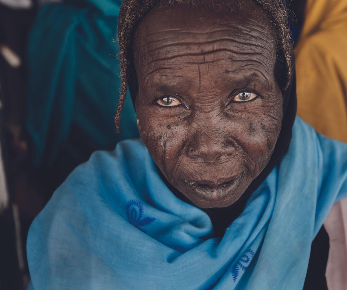 Todas las mujeres hablaban con ella en voz alta. La llamaban Hajje. Sus oídos no eran los de antaño. No sabía su edad. Tuvo que huir en 2003 y regresó a Tawila, su pueblo, años más tarde. Lucía el porte de una gran dama. Ese día no había comido, ni bebido leche ni té. Estaba sentada, esperando su turno en una clínica móvil de Médicos Sin Fronteras, a las afueras de Tawila. Hablaba pausada, encogida en sus recuerdos, y no dejaba de mirar y sonreír. (Tawila, Sudán, 2010).