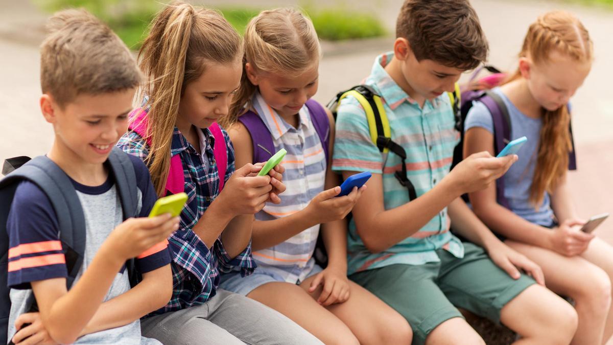 Un grupo de niños, de cara a sus teléfonos móviles.
