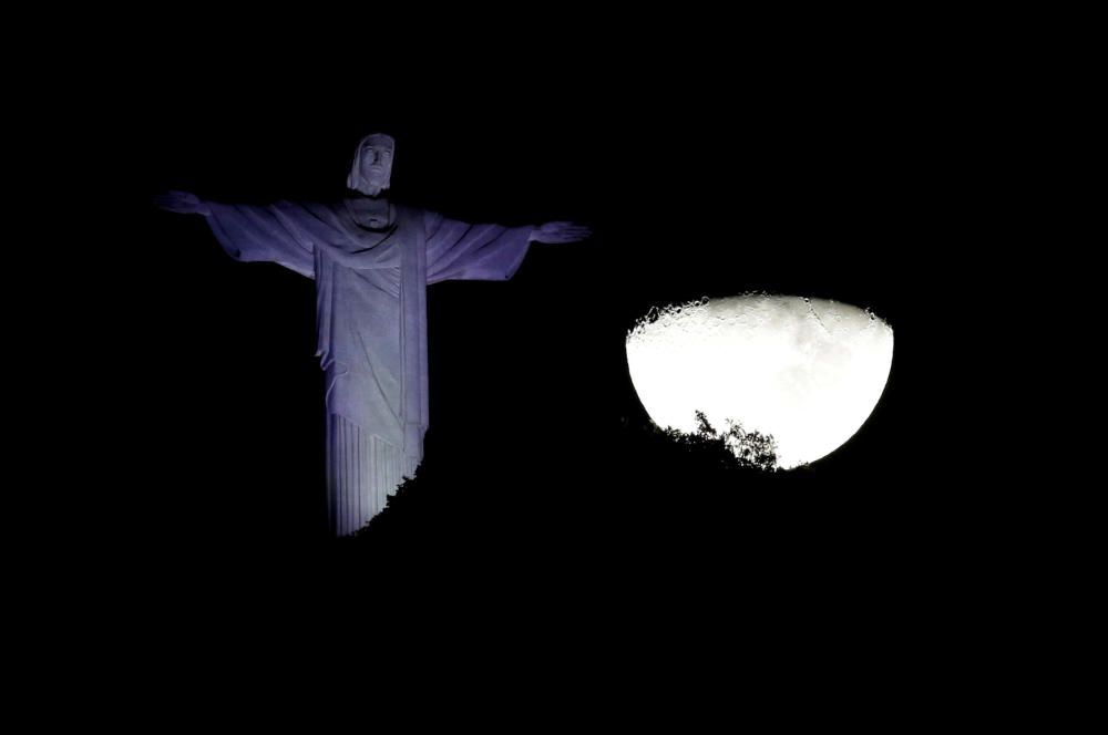 The moon is seen next to the Christ the Redeemer ...