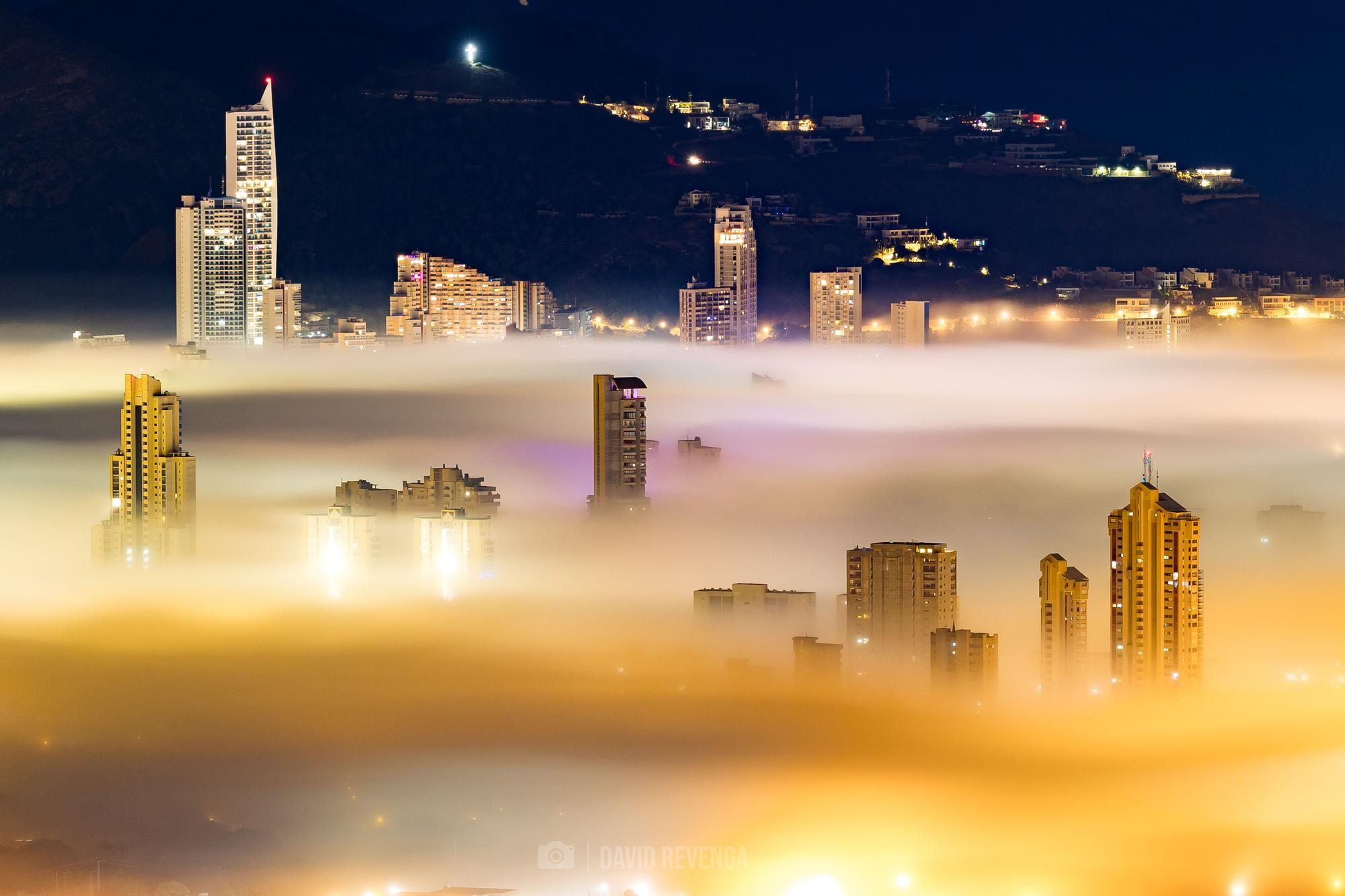 Una columna de niebla que ha entrado desde el mar ha "engullido" las playas y los edificios más cercanos a la primera línea de Benidorm, dejando imágenes del todo singulares de la ciudad.