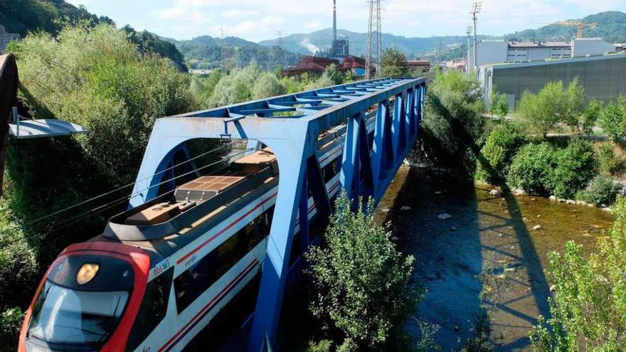 Un tren de la línea Oviedo-El Entrego circula por el puente sobre el río Nalón entre La Felguera y Sama.