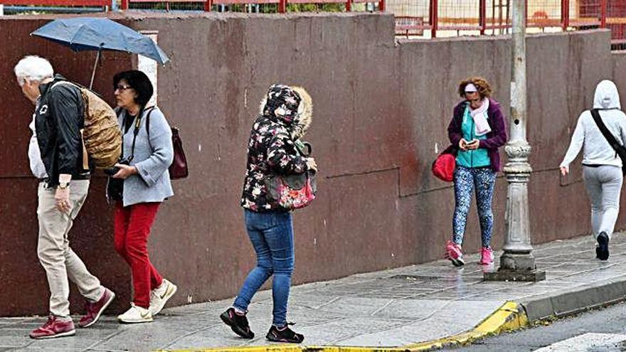 Vecinos de Telde intentan cubrirse, ayer, de la lluvia.