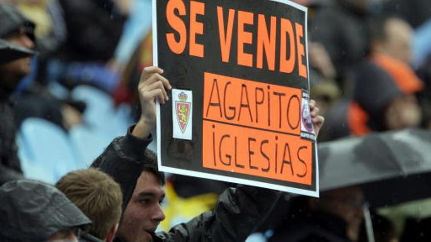 Un aficionado muestra un cartel alusivo al presidente del Real Zaragoza, Agapito Iglesias.