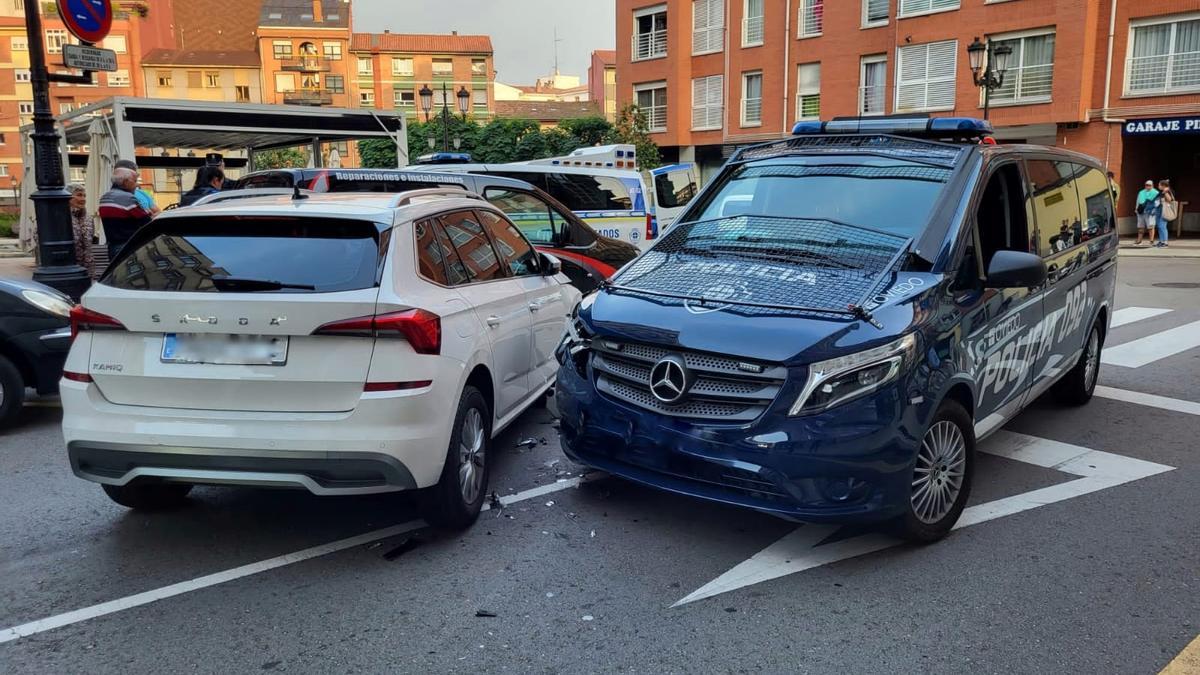 El vehículo implicado y el furgón policial tras el choque, en la calle Evaristo Valle de Oviedo.