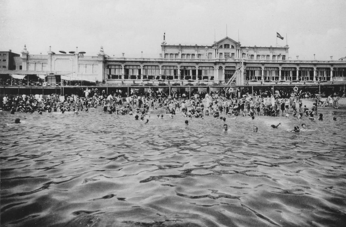 Vista desde el mar de la playa llena de gente y de los baños de Sant Sebastià