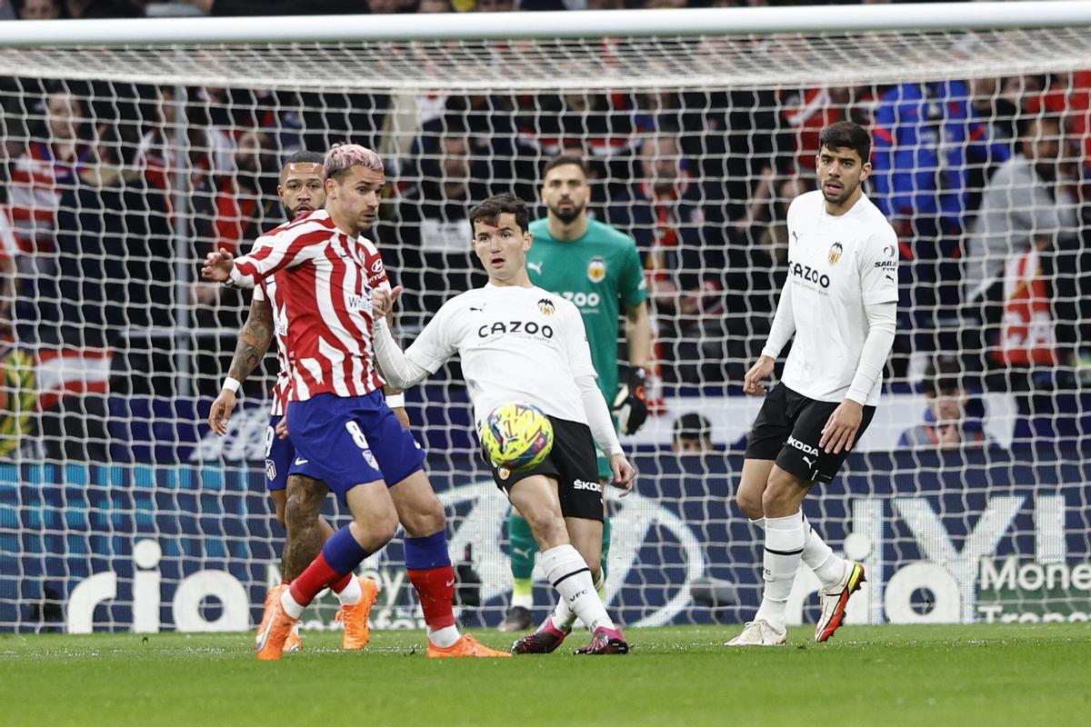 MADRID 18/03/2023.- El delantero francés del Atlético de Madrid Antoine Griezmann (i) disputa una posesión con el defensa del Valencia Hugo Guillamón (c) durante el partido de la jornada 26 de LaLiga Santander que disputan con el Atlético de Madrid este sábado en el Cívitas Metropolitano de Madrid. EFE/ Rodrigo Jimenez