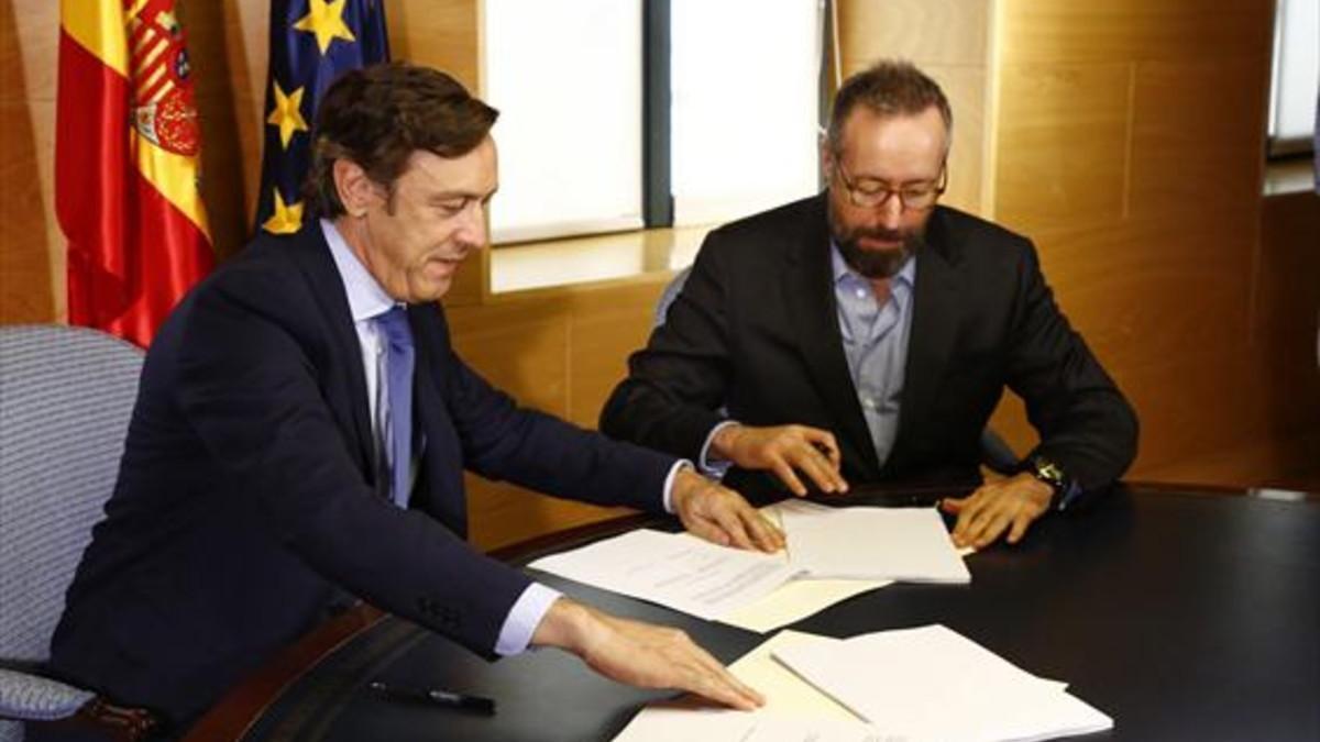 Rafael Hernando (izqda.) y Juan Carlos Girauta firman el acuerdo, ayer.