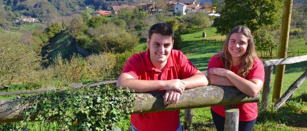 Efrén García y Lucía Cuesta, en el exterior de su local, con parte del pueblo de Acebedo tras ellos.