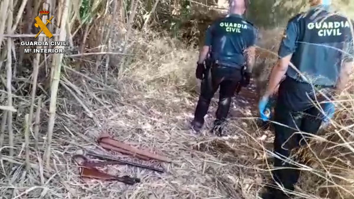 Dos agentes dela Guardia Civil junto a la escopeta encontrada en el campo.