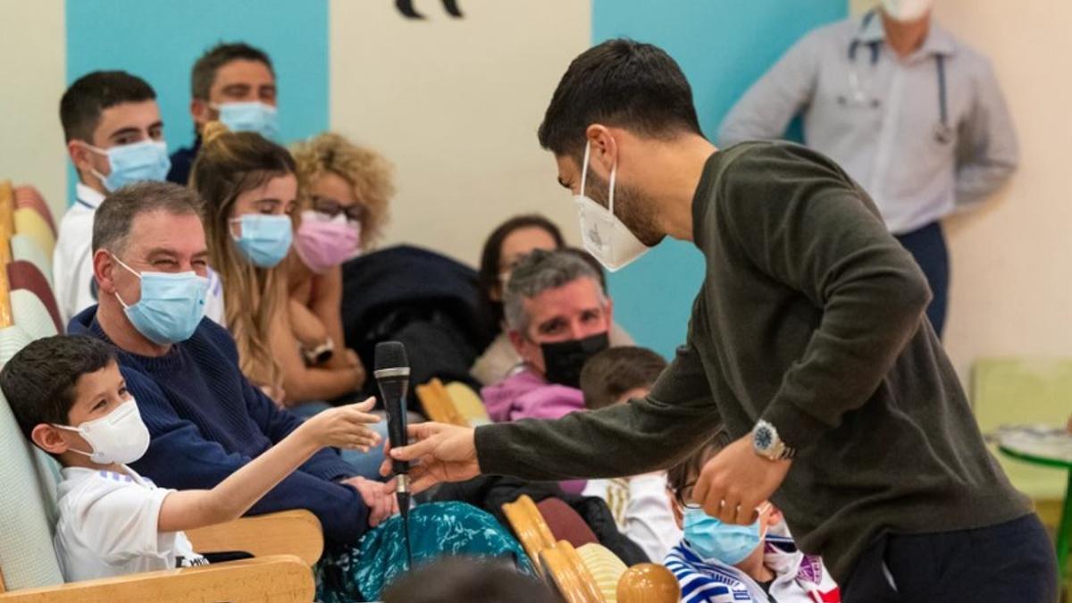 Marco Asensio, bromea con un niño, en la presentación de su nueva Fundación.