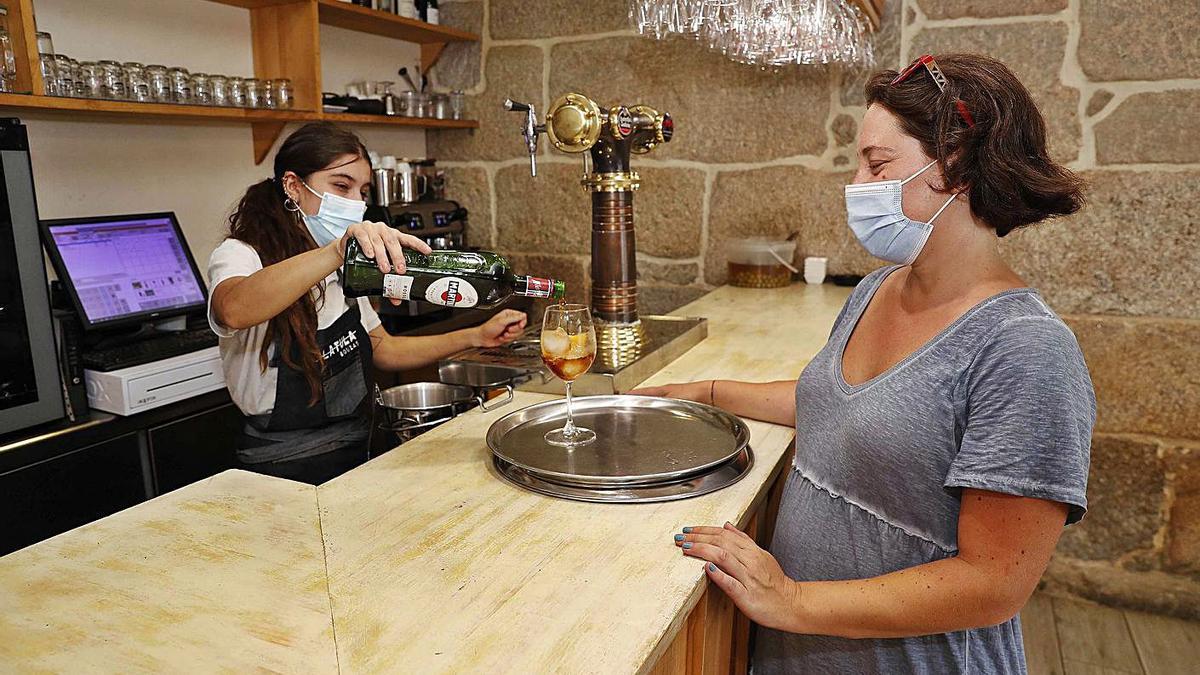 Bibiana López recoge un Martini en la barra de su local de Bouzas. |   // PABLO HERNÁNDEZ