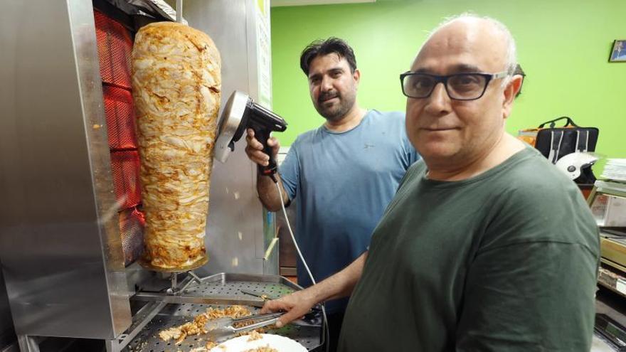 Ashgar (en primer término) y Yasir preparan uno de los ricos kebabs de su local en la zona monumental.