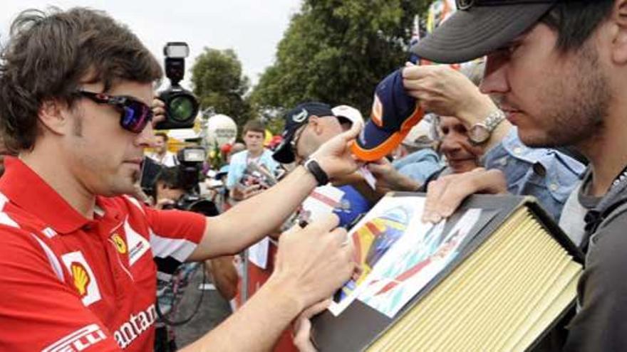 Alonso firma autógrafos antes de la primera sesión de entrenamientos en el circuito de Albert Park