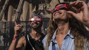 Algunes persones proven les ulleres homologades de cara a l’eclipsi, a l’entorn de la Sagrada Família. | ZOWY VOETEN