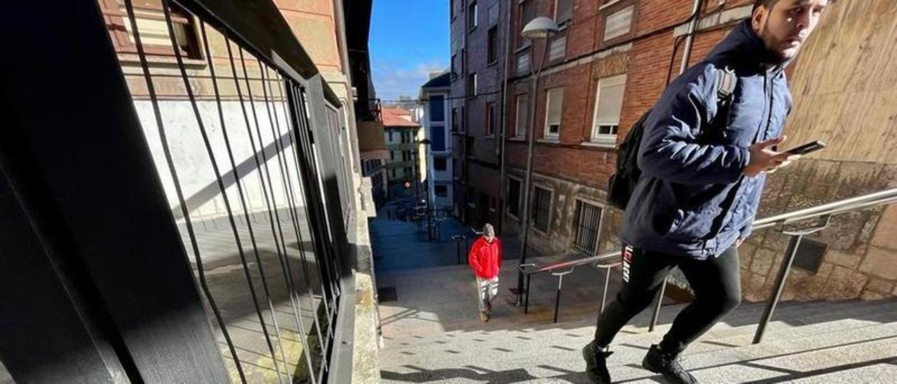 Dos vecinos suben las escaleras que unen el centro urbano de Pola de Lena con la estación de tren.