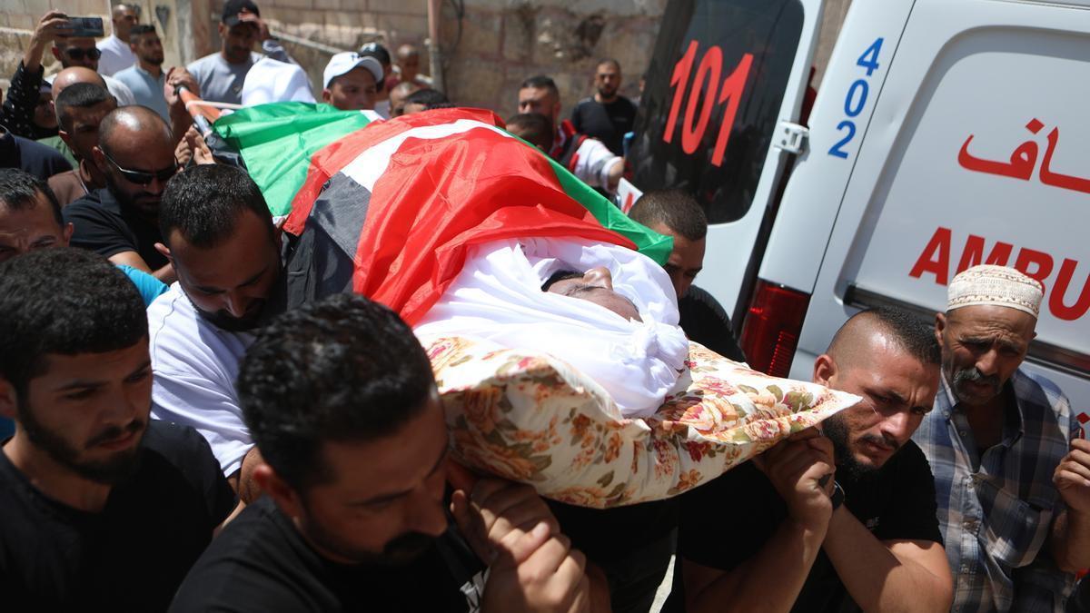 Varios hombres llevan a un palestino muerto por un ataque israelí en Cisjordania.