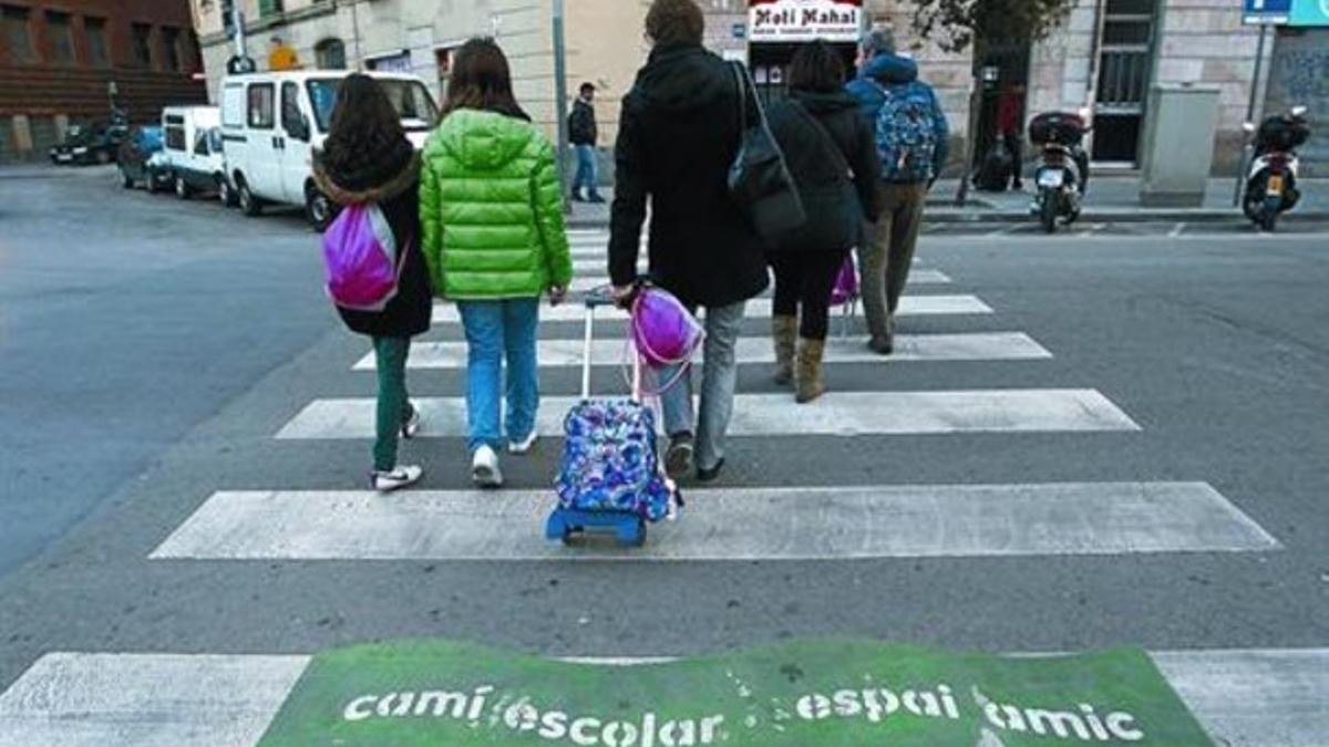 Varios peatones, ayer, en el Raval tras la salida del colegio cruzando por un paso marcado como camino escolar.