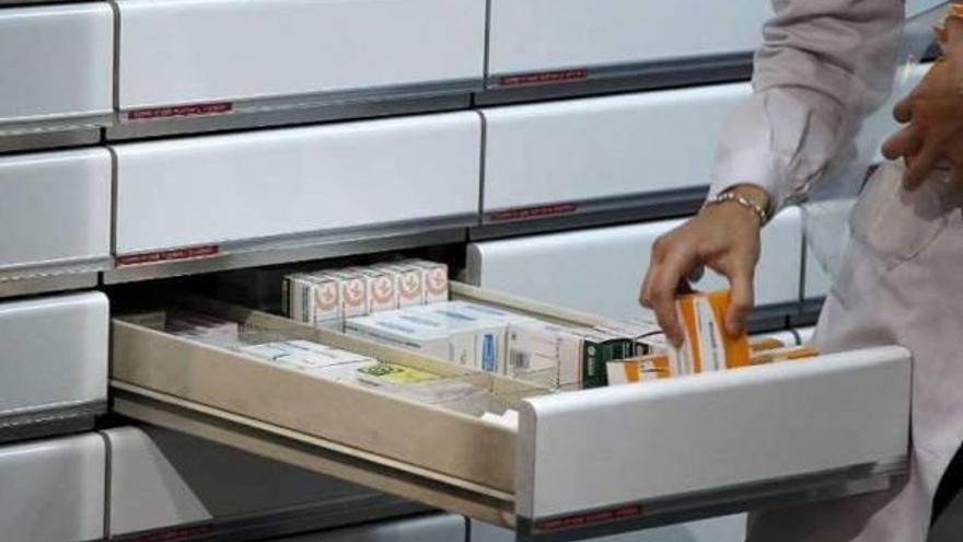 Una farmacéutica coloca varios medicamentos en un cajón.