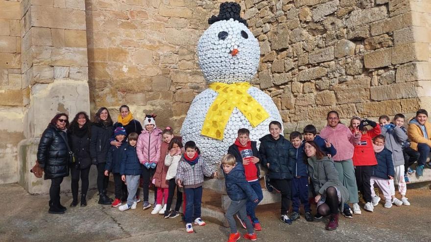 Escolares del colegio de Cañizal junto a la bufanda amarilla que han colocado al muñeco de nieve. | Cedida