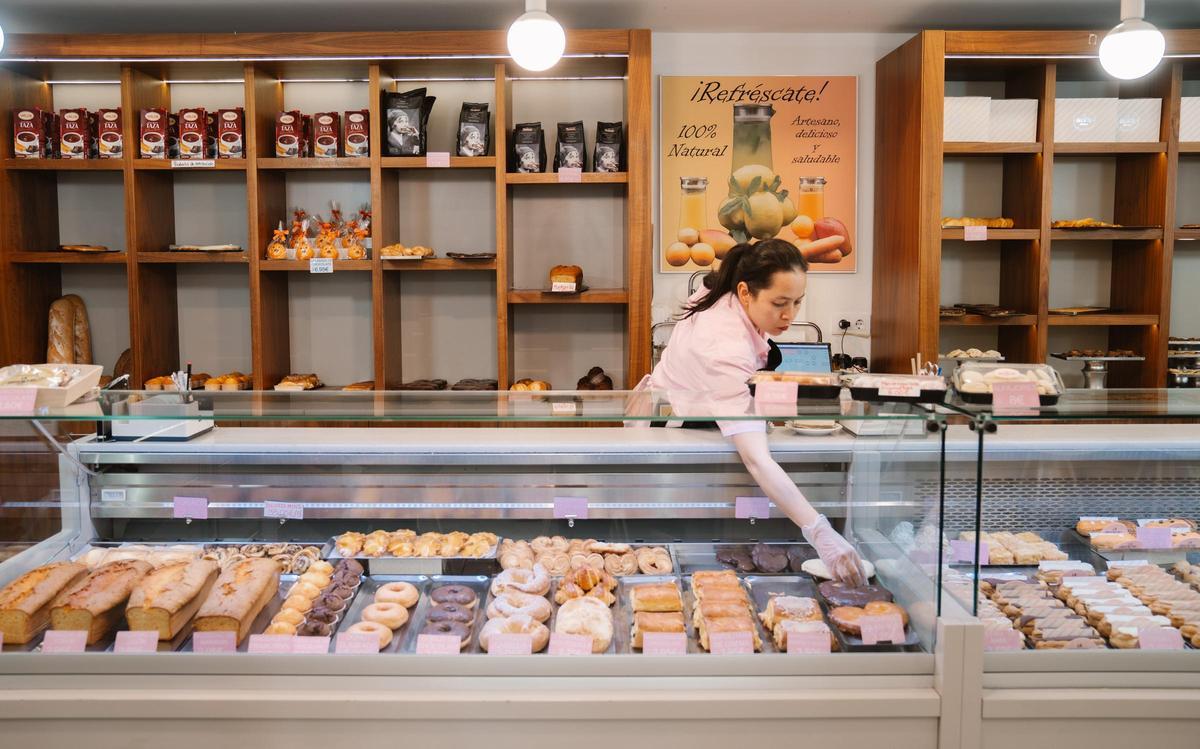 Una trabajadora de la cafetería-pastelería de La Oriental coloca productos en el mostrador.