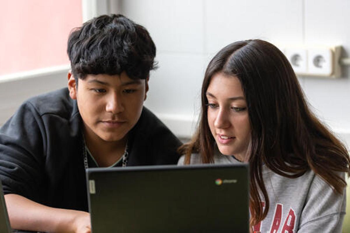 Dos joves llegint un contingut en un ordinador