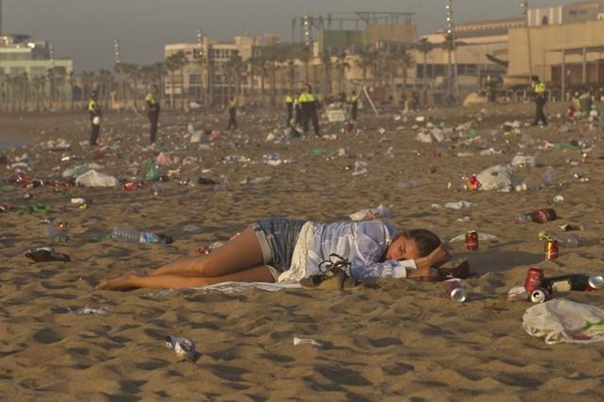 Una noia dorm a la platja de la Barceloneta després de la nit de celebració.