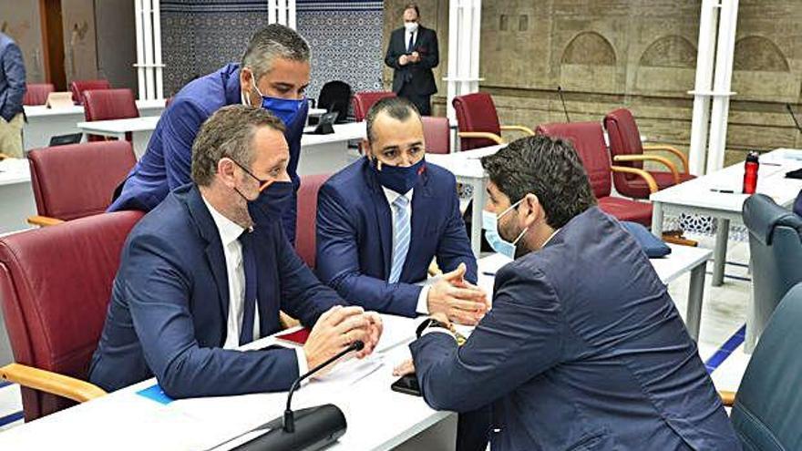 Fernando López Miras charla con los diputados del PP Joaquín Segado, Jesús Cano y Juan Antonio Mata en su escaño.