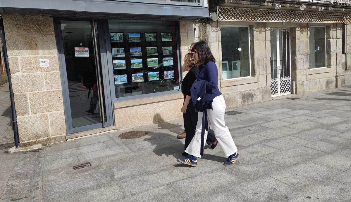 Vecinos de Cangas, paseando delante de una inmobiliaria en el centro de la villa. | GONZALO NÚÑEZ