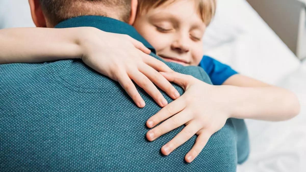 Un padre abrazando a su hijo.