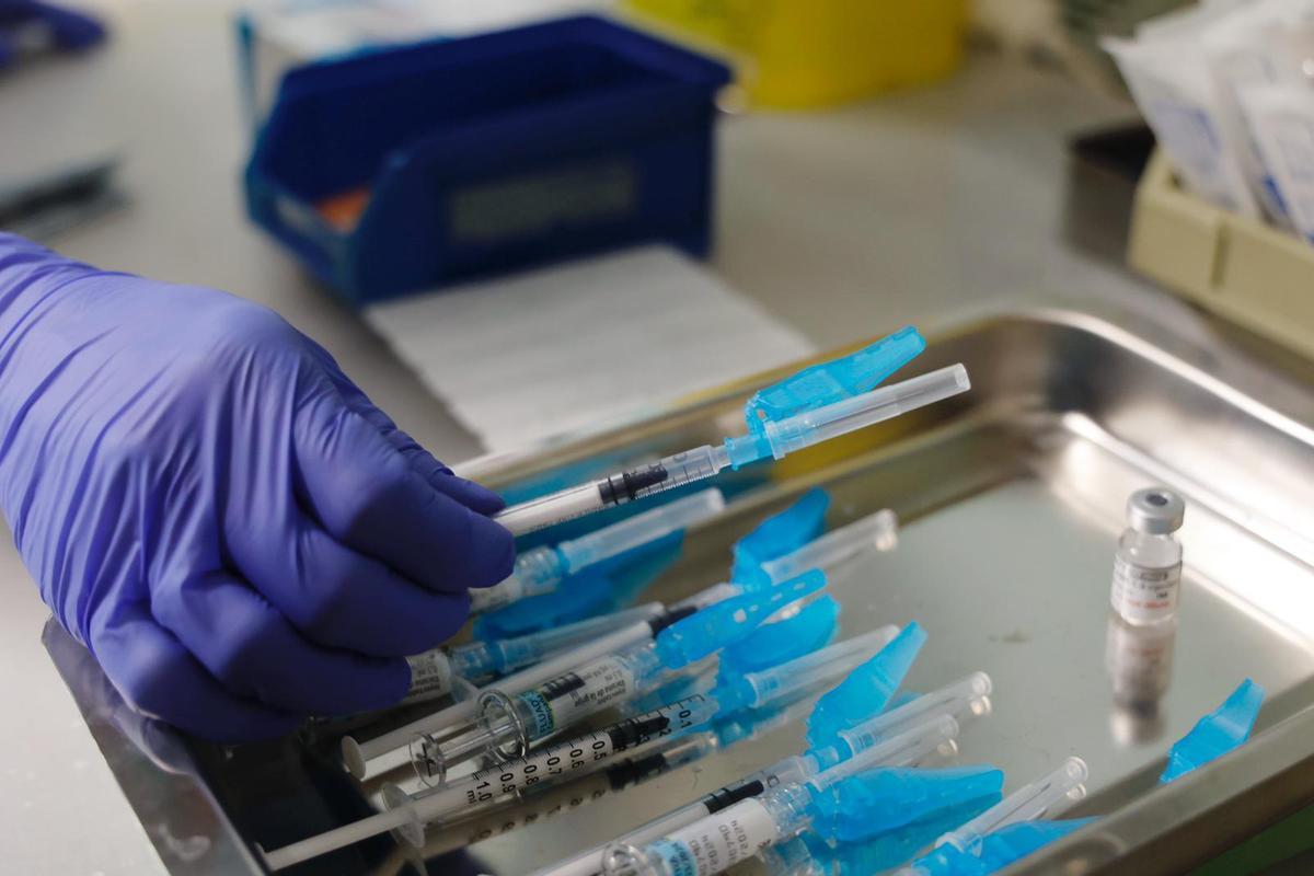 Un sanitario prepara una jeringa para poner la vacuna de covid y gripe.
