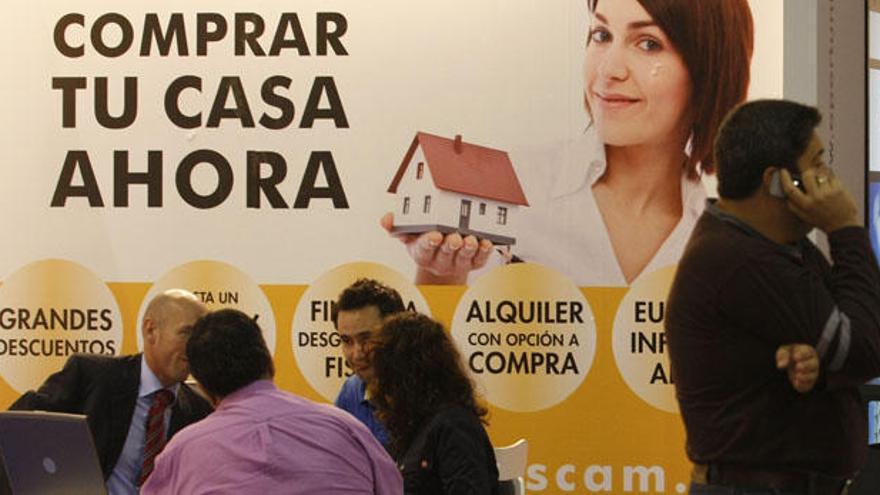 Clientes negocian la compra de una vivienda en un salón inmobiliario.
