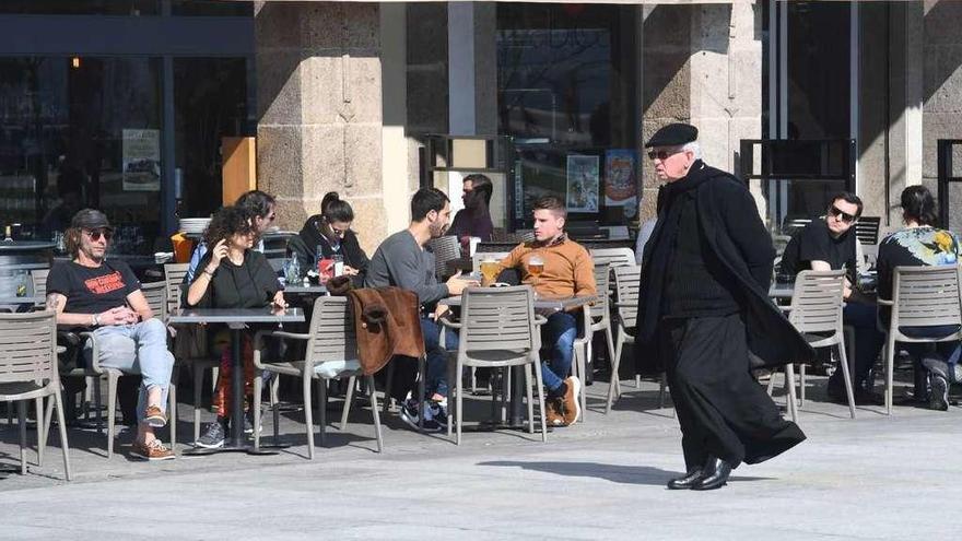 Un sacerdote pasa por delante de las terrazas de la Marina.