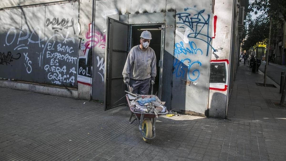 Un operario saca restos de la obra del local conocido como 'banco expropiado', en Gràcia.