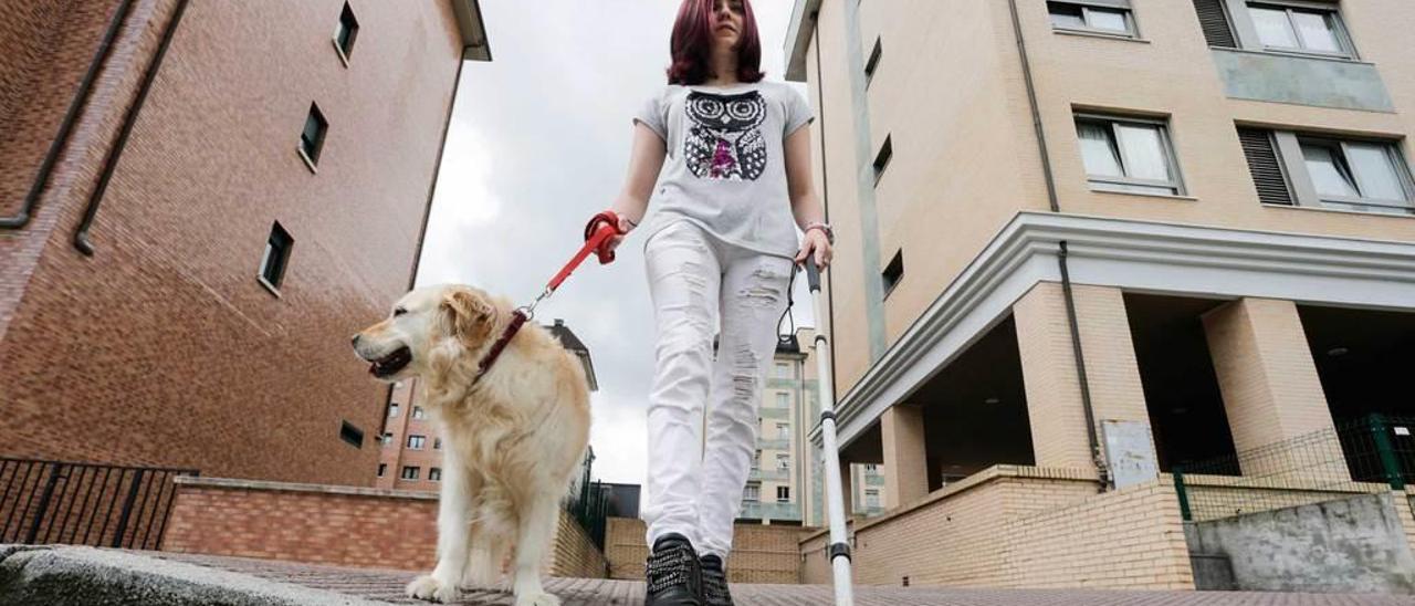 La joven Carmen López, con su perra &quot;Luna&quot;, muestra cómo un camino de baldosas punteadas la lleva a una salida de un garaje y directamente a la mitad de la carretera de la calle Santiago de Compostela, en Ciudad Naranco.