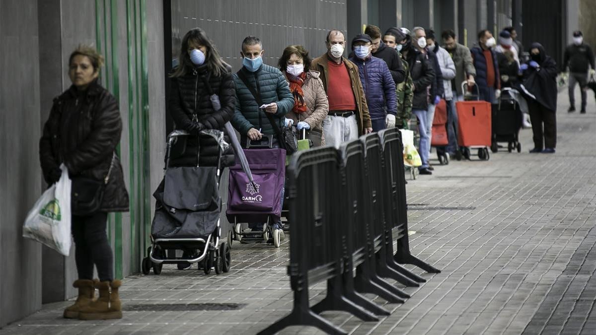 Colas de gente con mascarilla  en un supermercado de l'Hospitalet