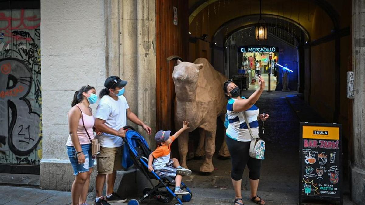 Unos turistas se fotografían con el camello que preside la entrada de las galerías El Mercadillo.