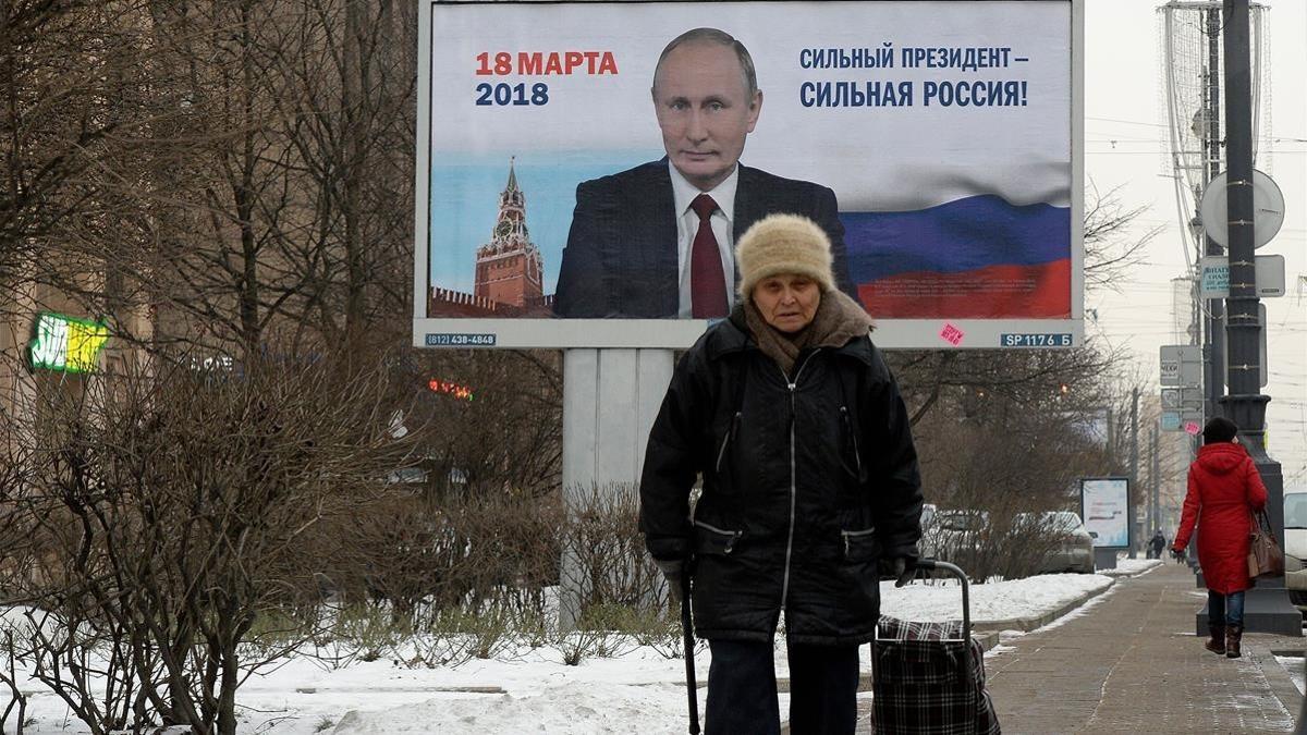 Una mujer pasa ante un espacio publicitario con la imagen de Putin y la leyenda 'Un presidente fuerte es un país fuerte', en San Petersburgo, el 12 de enero.