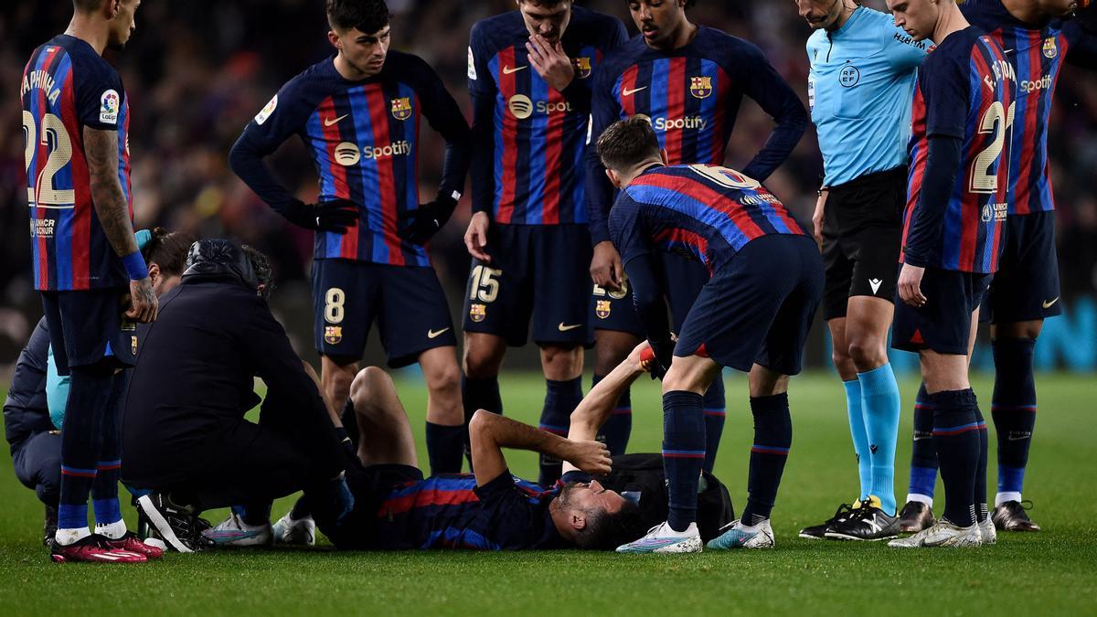 Busquets es atendido de su esguince en el tobillo izquierdo, observado por sus compañeros en el Barça-Sevilla del Camp Nou.