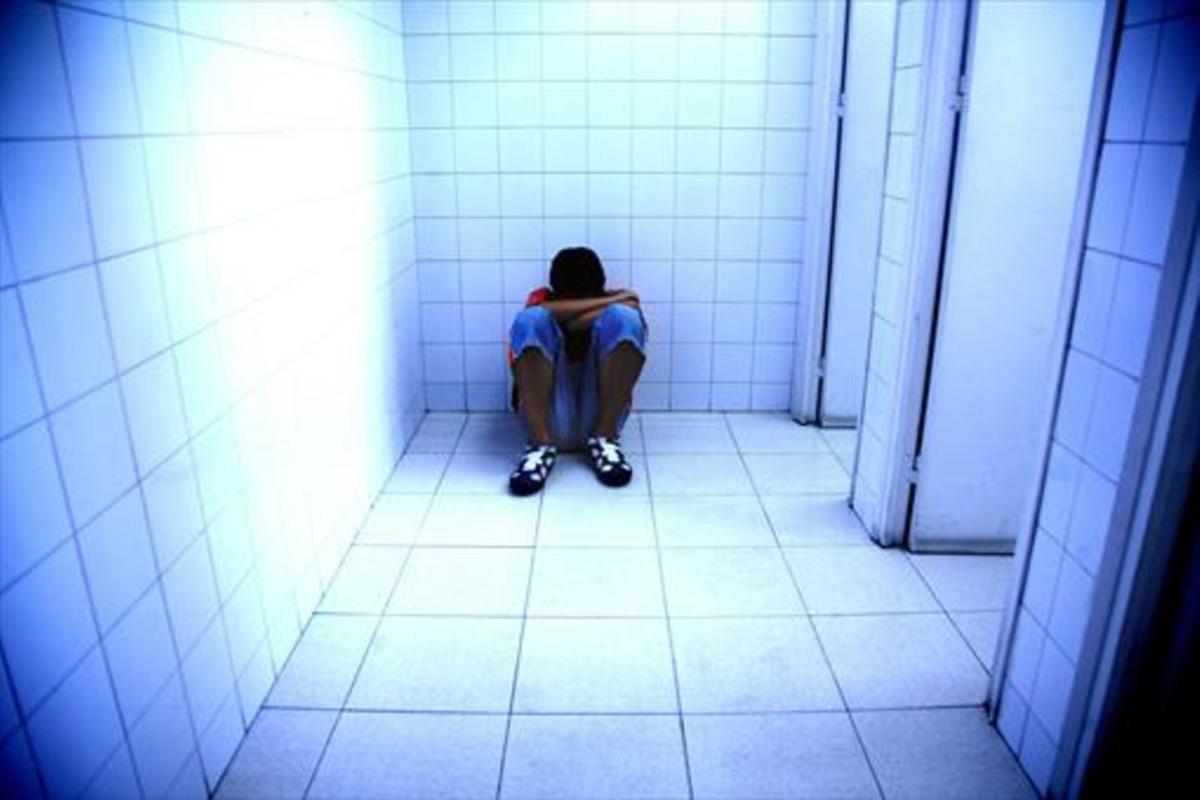 Un joven, víctima de acoso escolar, se refugia en un lavabo.