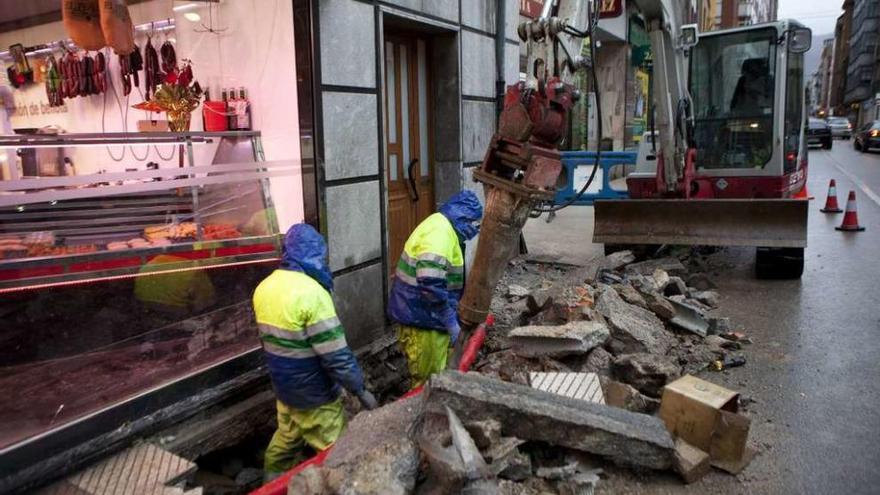 Dos operarios, trabajando en la reparación de una avería en la calle Constitución de Sama en enero.