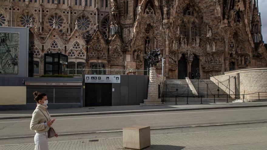 Una mujer con mascarilla, ante la Sagrada Familia.